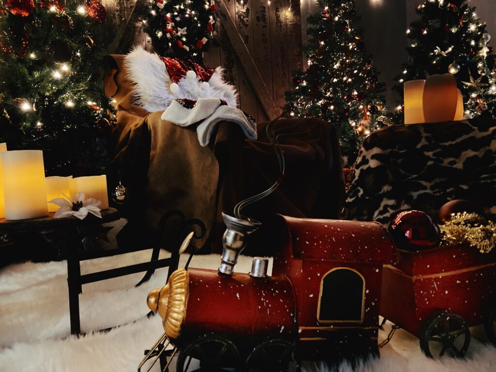 Im Mittelpunkt steht ein Shabby-Hintergrund mit alter Scheunentür, der den perfekten Vintage-Touch liefert. Dazu gesellen sich drei große, festlich geschmückte Weihnachtsbäume, funkelnde Lichterketten, weiche Felle, edle echte Lederhäute